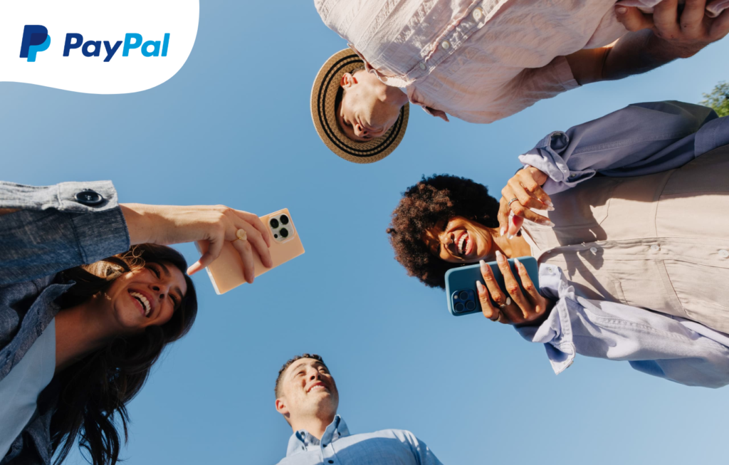 Giovani amici sorridenti che usano PayPal per inviare denaro con lo smartphone