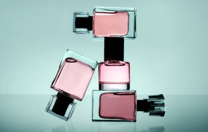 Flaconi di profumo in vetro con essenza rosa su sfondo chiaro