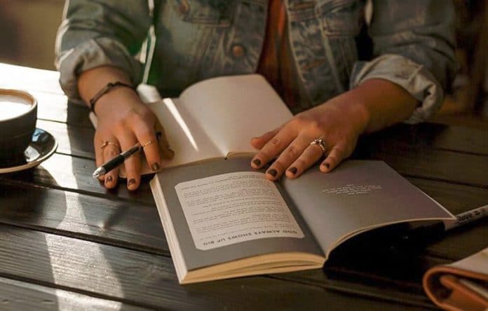 Donna che legge un libro e prende appunti sul quaderno