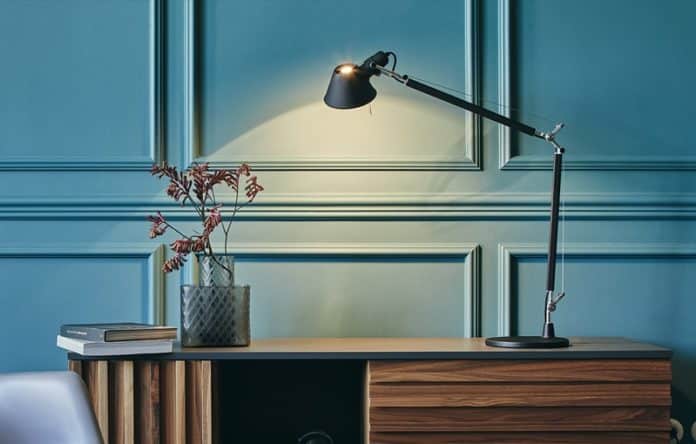 ampada da tavolo Artemide Tolomeo accesa su scrivania moderna, esempio di illuminazione funzionale per interni