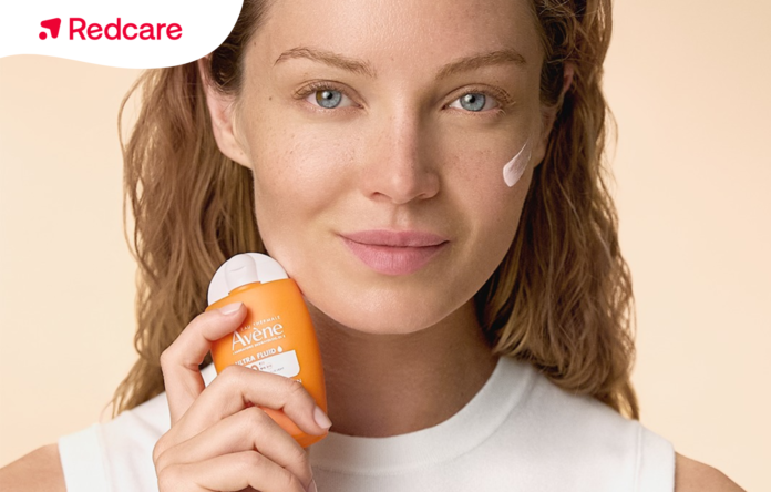 Donna che applica una crema solare per il viso, disponibile in offerta su Redcare