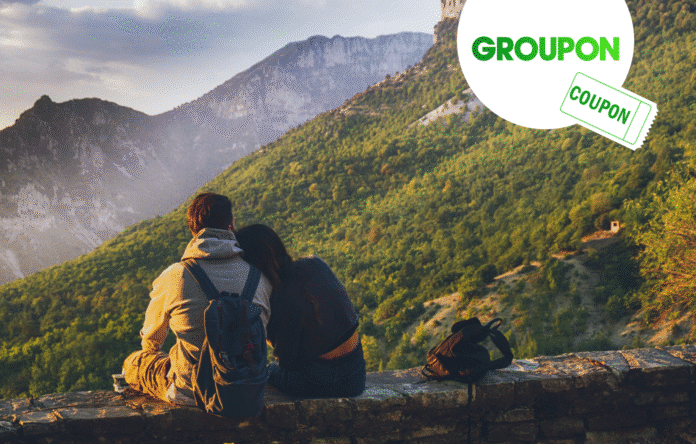 Coppia che ammira il panorama in montagna con logo Groupon Coupon per viaggi e sconti Topnegozi