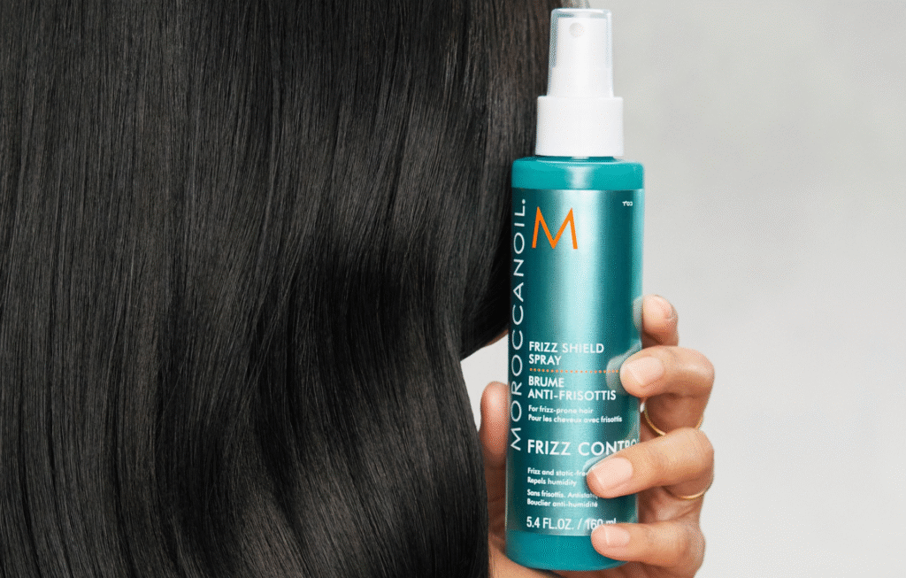 Donna con capelli lunghi e neri applica spray trattamento ristrutturante Maroccanoil